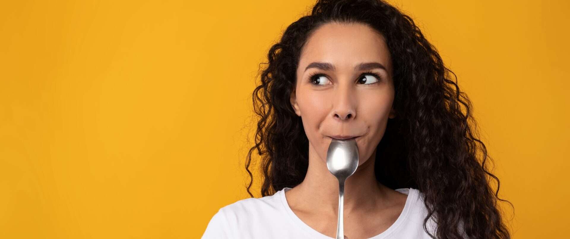 スプーンを口にくわえた女性。彼女は英語の発音を練習しています。