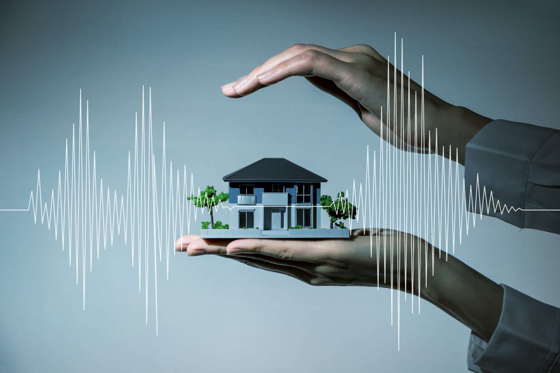 音波を背景に家の模型を持つ手。