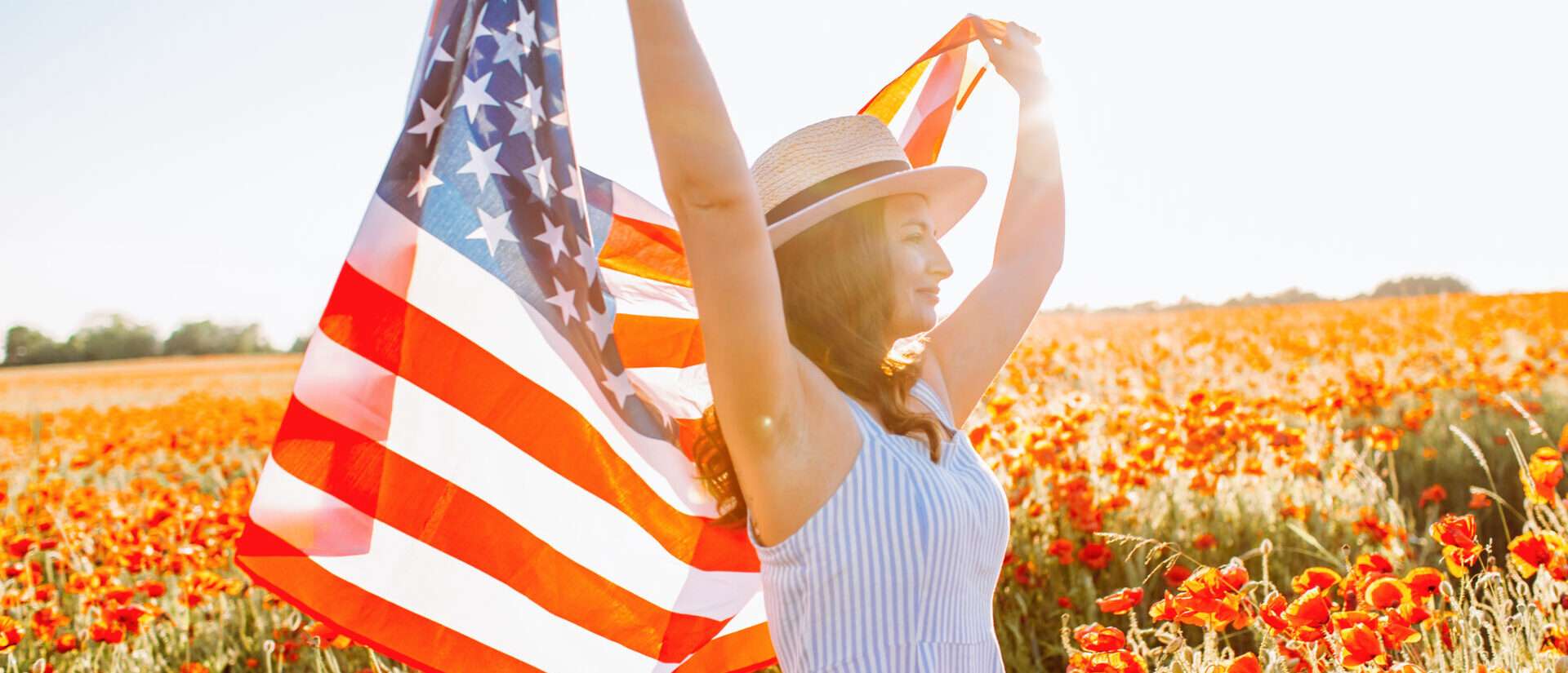 ケシ畑でアメリカ国旗を掲げる女性。