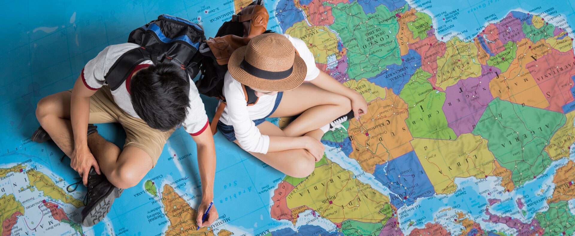 地図の上に座って勉強している 2 人。