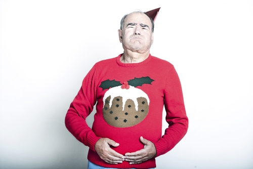 魅力的なツリーのデザインが施されたクリスマス セーターを着て、英会話に興じる男性。