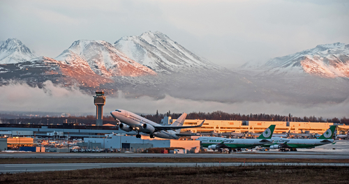 雪山を背景に空港から飛行機が離陸します。このシーンでは、飛行機が旅を始めるときに、雪に覆われた山々の息を呑むような美しさが表現されています。
