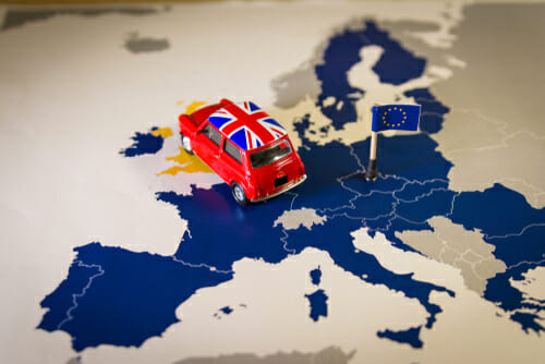 ヨーロッパの地図の上におもちゃの車が置かれ、周りには英語の教材や会話ガイドが散らばっています。