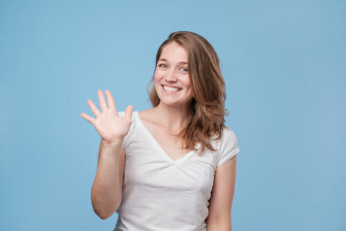 青い背景に、英会話中に身振り手振りをする若い女性。
