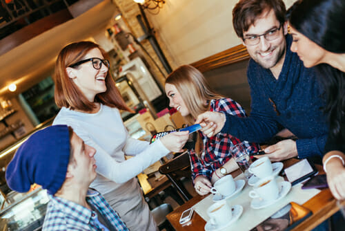 カフェのテーブルの周りに座って英会話に取り組む人々のグループ。