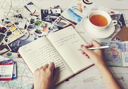 女性がお茶を楽しみながらノートに書いています。