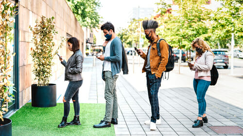 歩道に立って携帯電話に夢中になっている人々のグループ。