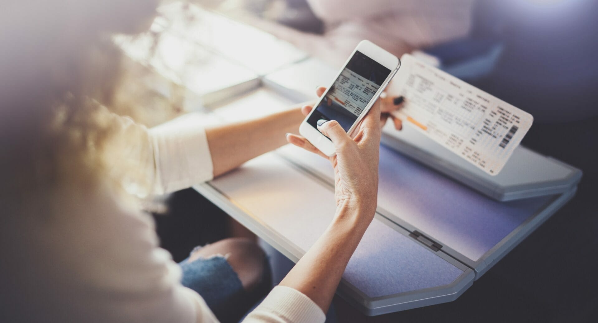 女性が携帯電話を使って英語の搭乗券を確認しています。