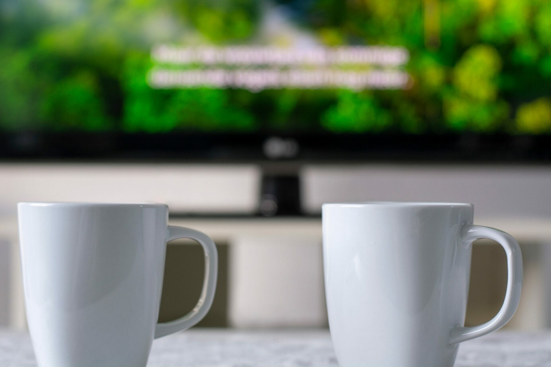 テレビの前のテーブルの上に 2 つのコーヒー カップが置かれています。