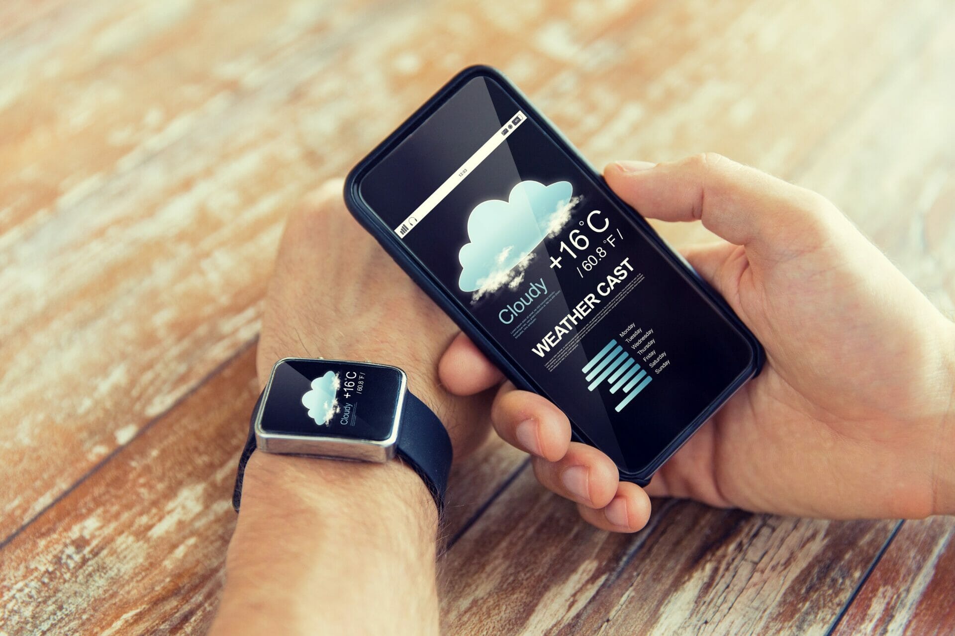 人は天気アプリが入ったスマートフォンを持っています。その人は天気予報をチェックしているようだ。