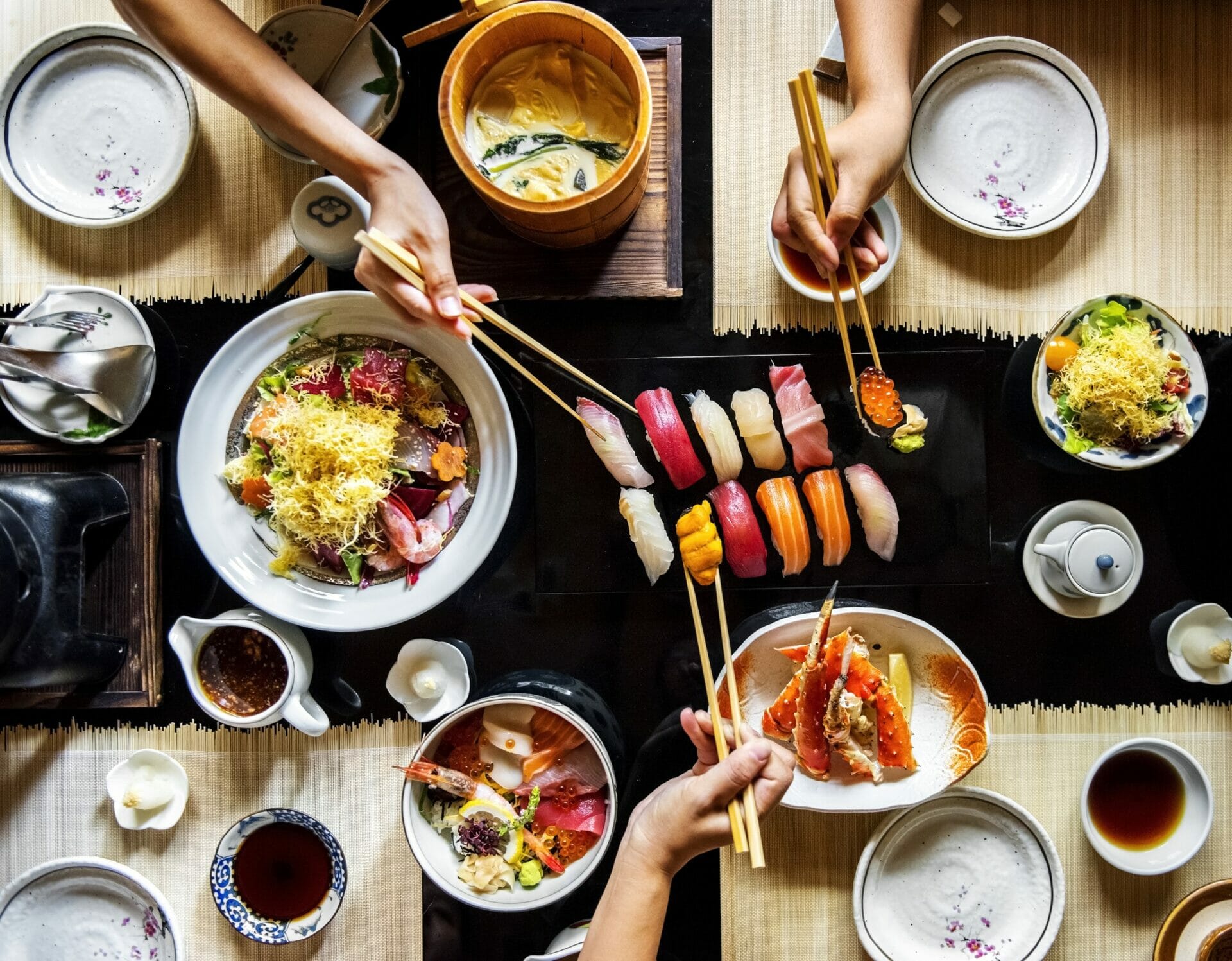 テーブルで日本料理を楽しむ人々のグループ。