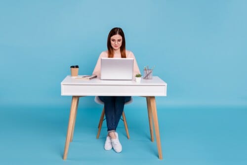 机に座ってラップトップを使用して英語を話す女性。