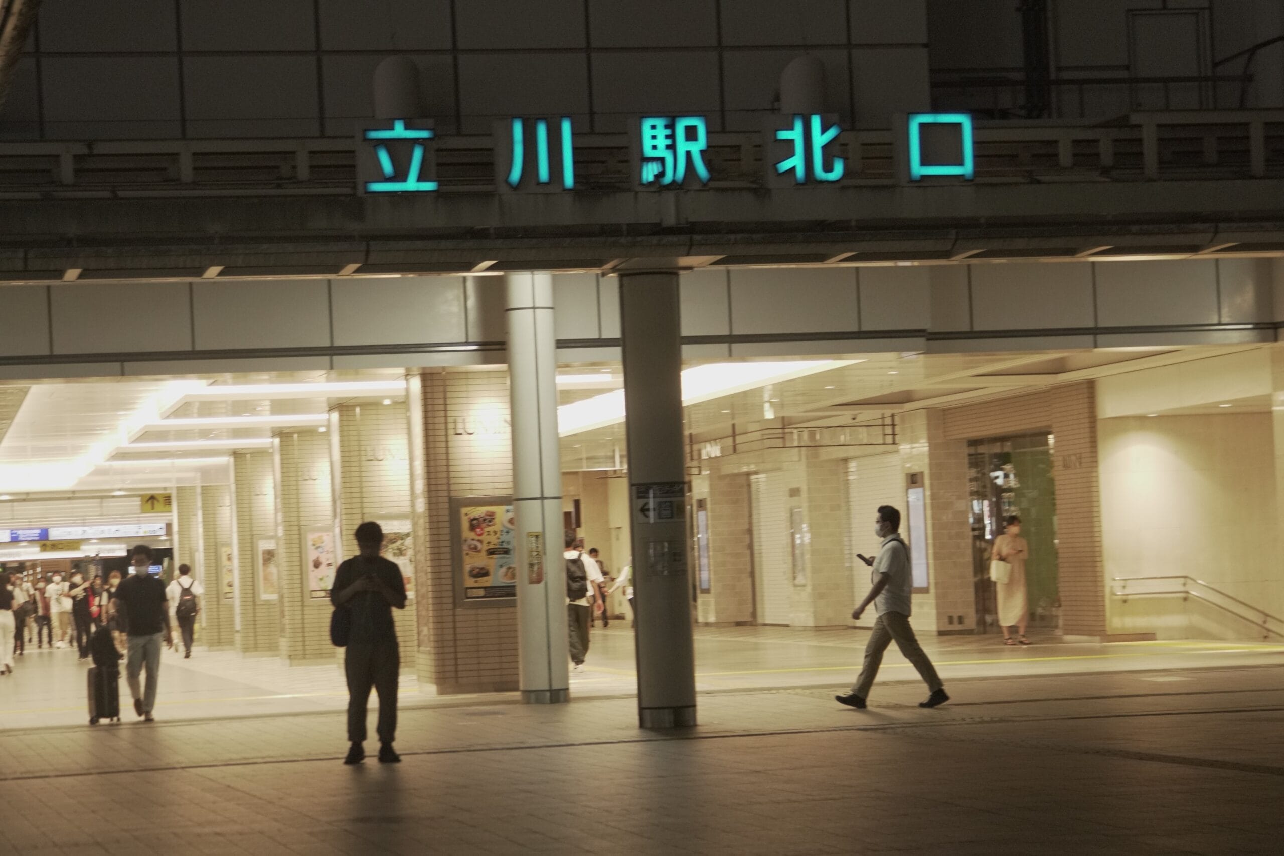 電飾看板と駅入口が目を引く立川駅北口の外を歩く人たち。近くの英会話スクール マンツーマンは、賑やかな立川で個人に合わせた語学レッスンを提供しています。.