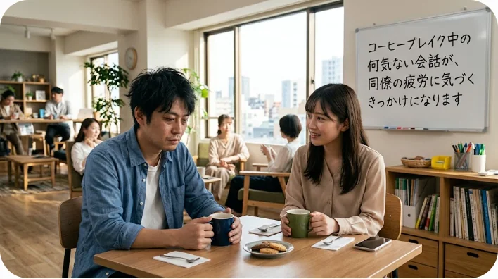 モダンなオフィスのパントリーでコーヒーを片手に共感し合いながら会話する二人の同僚