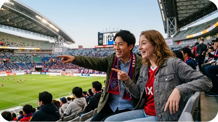 スタジアムで並んで座り、興奮した様子でアリーナを指さしながら話す日本人と外国人の友人